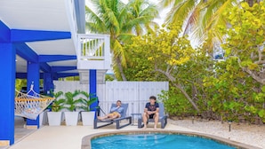 A pool area with two lounge chairs, a hammock, and potted plants. - Ocean front paradise in Little Torch Key (Little Torch Key)