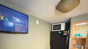 A small kitchenette with a microwave, refrigerator, and a flat-screen TV displaying a setup guide. - Cozy Craftsman Home Close to UW and Downtown (Laramie)