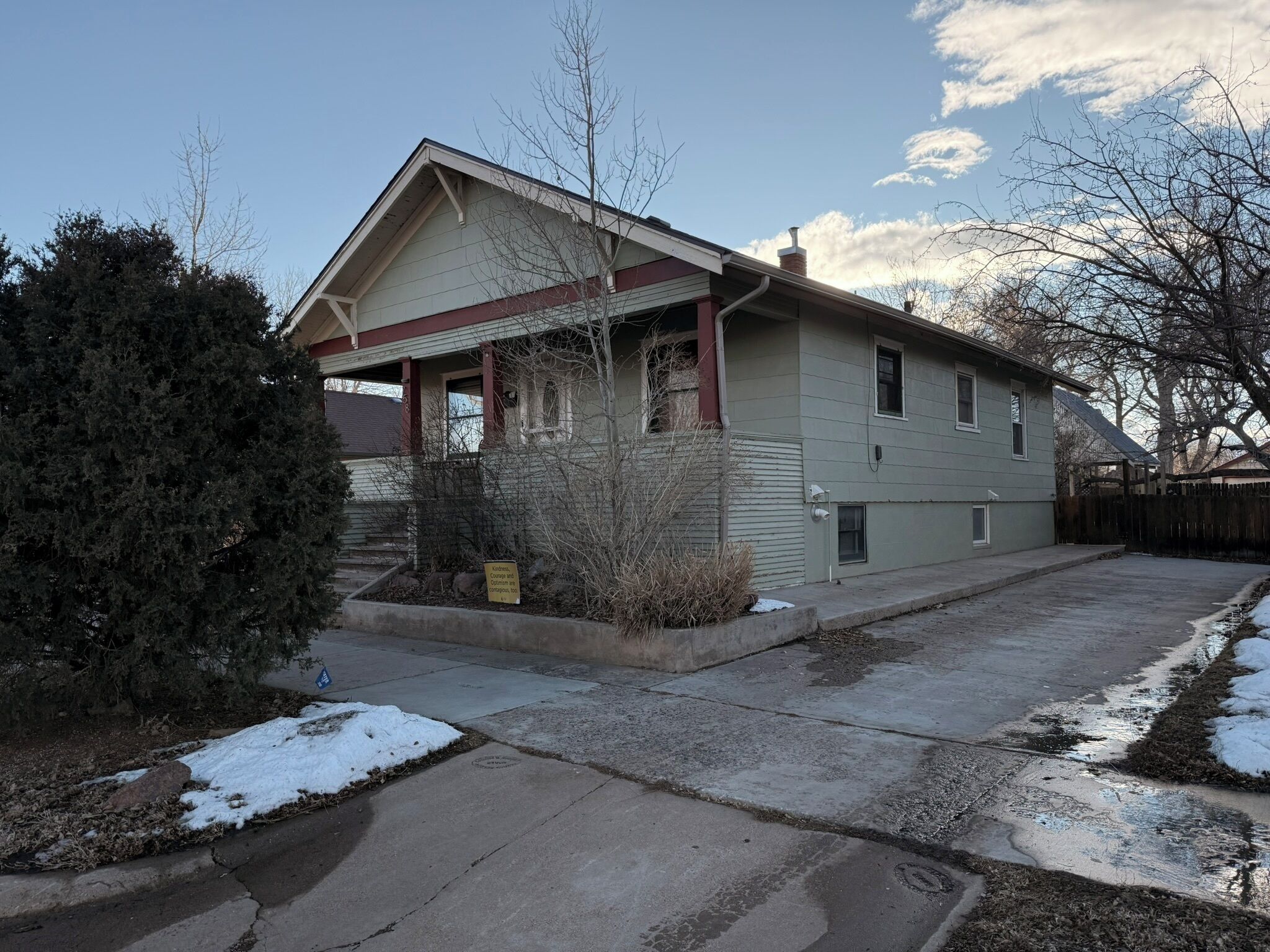 Ein zweistöckiges Haus mit Veranda, Garage und einem eingezäunten Garten.