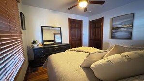 A bedroom with a bed, dresser, ceiling fan, and a painting on the wall. - Cozy Craftsman Home Close to UW and Downtown (Laramie)