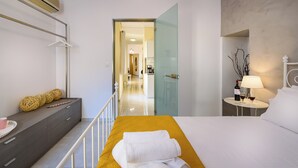 A modern hotel room with a bed, bedside table, and a view of the hallway.