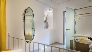 A hotel room with a bed, a bathroom with a mirror, a wardrobe, and a small table with a glass of wine and orange juice.