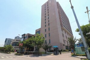 A multi-story building with a modern architectural design, featuring a prominent entrance and a visible entrance gate. - Xinzhuo Select Hotel (Shanghai)