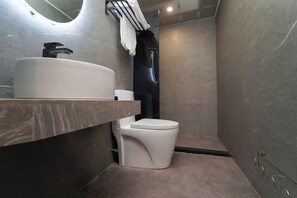 A modern bathroom with a built-in sink, toilet, and a towel hanging on the wall. - Xinzhuo Select Hotel (Shanghai)