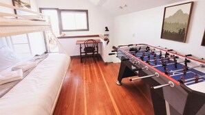 Una habitación con cama, escritorio, silla y mesa de futbolín.