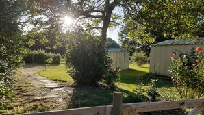 A wooden gate leading to a garden with a path, surrounded by greenery and a shed. - QUIETLY SITUATED VACATION HOME (Azerables)