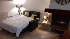 A bedroom with a bed, a lamp, a clock, and a fireplace. - QUIETLY SITUATED VACATION HOME (Azerables)