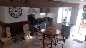 A kitchen with modern appliances, a dining area with a round table and chairs, and a fireplace. - QUIETLY SITUATED VACATION HOME (Azerables)