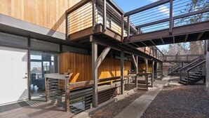 Een modern gebouw met houten lambrisering, metalen leuningen en een trap naar een hoger gelegen verdieping.