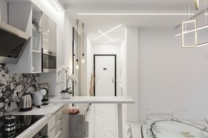 Una cocina moderna con armarios blancos, una salpicadura de mármol y una isla central.