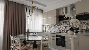 A modern kitchen with a marble backsplash, a central island, and a dining area with a round table and cushioned chairs.