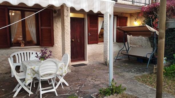 Un patio con una mesa y sillas, una puerta de madera y un pequeño jardín.