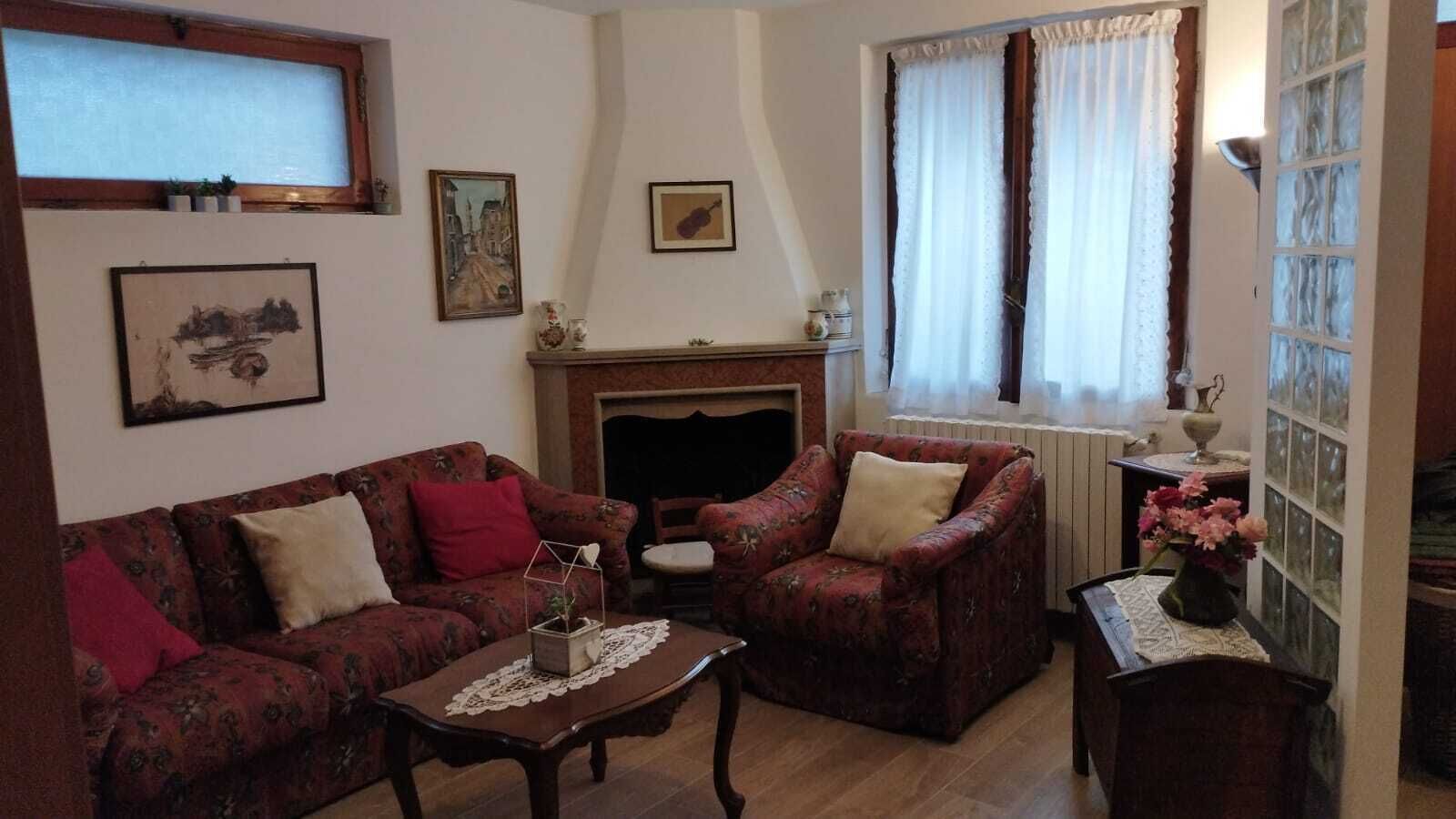Un salon comprenant un canapé, un fauteuil et une petite table sur laquelle est posé un vase de fleurs.