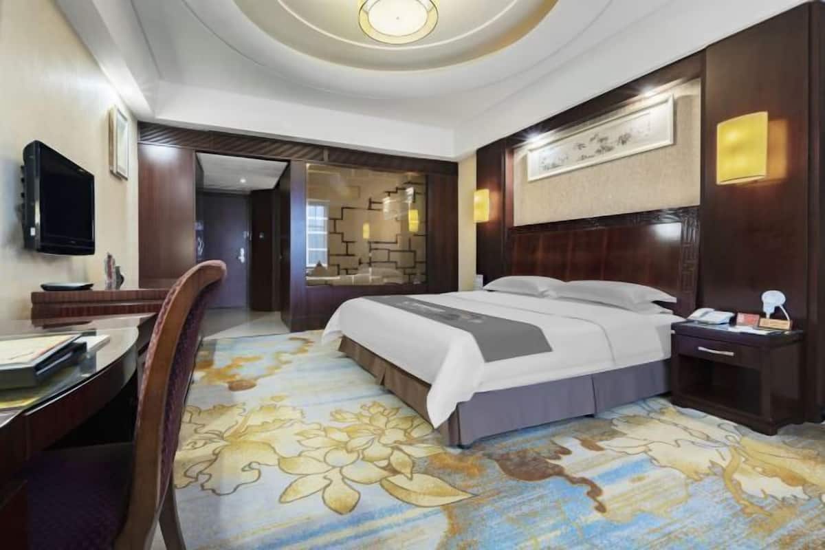 A hotel room with a bed, desk, and TV.