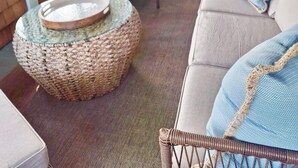 A covered patio area with wicker furniture, a round woven table, and a cushioned sofa. - Beach Cottage II, near the beach, TPC Sawgrass, Mayo Clinic & Ponte Vedra Beach (Jacksonville Beach)
