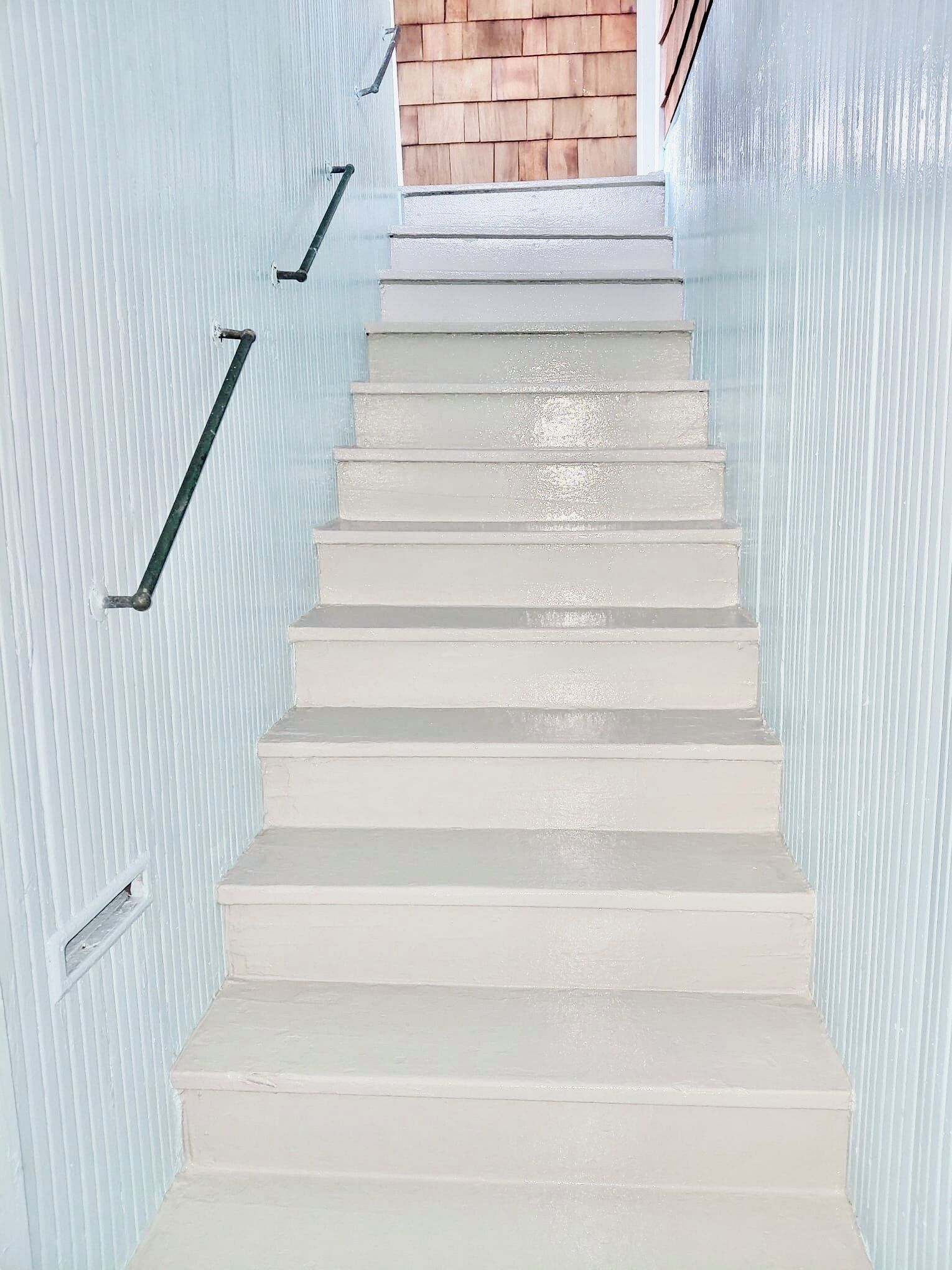 Una escalera blanca que conduce a una puerta de madera.