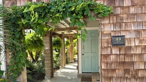 A wooden building entrance with a green door, a number plaque, and a covered walkway. - Beach Cottage II, near the beach, TPC Sawgrass, Mayo Clinic & Ponte Vedra Beach (Jacksonville Beach)
