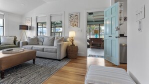 A living room with a sofa, a coffee table, and a lamp. There is a door leading to the kitchen. - Beach Cottage II, near the beach, TPC Sawgrass, Mayo Clinic & Ponte Vedra Beach (Jacksonville Beach)