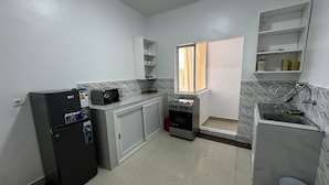 Eine kompakte Küche mit Kühlschrank, Mikrowelle, Herd und Spüle.