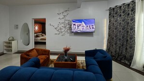 Ein modernes Wohnzimmer mit großem Flachbildfernseher, zwei Sofas, einem Couchtisch und einer Wanddekoration.