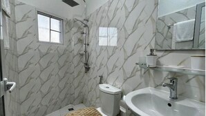 Ein Badezimmer mit Dusche, Toilette, Waschbecken und einem Fenster.