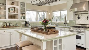 A kitchen with white cabinetry, a central island, and a stainless steel stove. - Luxury Wine Country Haven Vineyard Views Near Top Wineries Adelaida Farmhouse (Paso Robles)