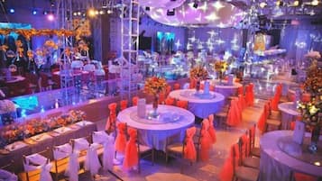 A banquet hall with round tables, chairs, and floral centerpieces.