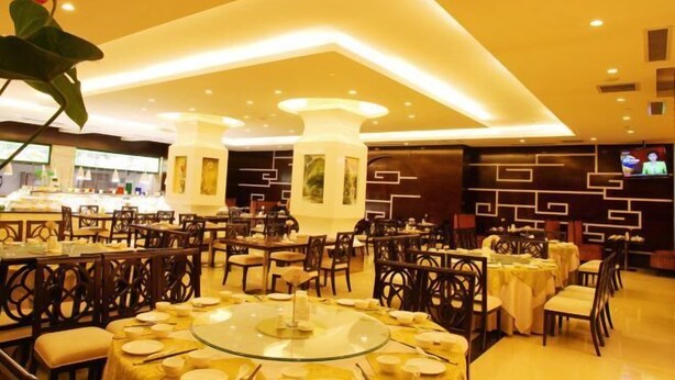 Un restaurante con mesas redondas, sillas y una pantalla de televisión en la pared.