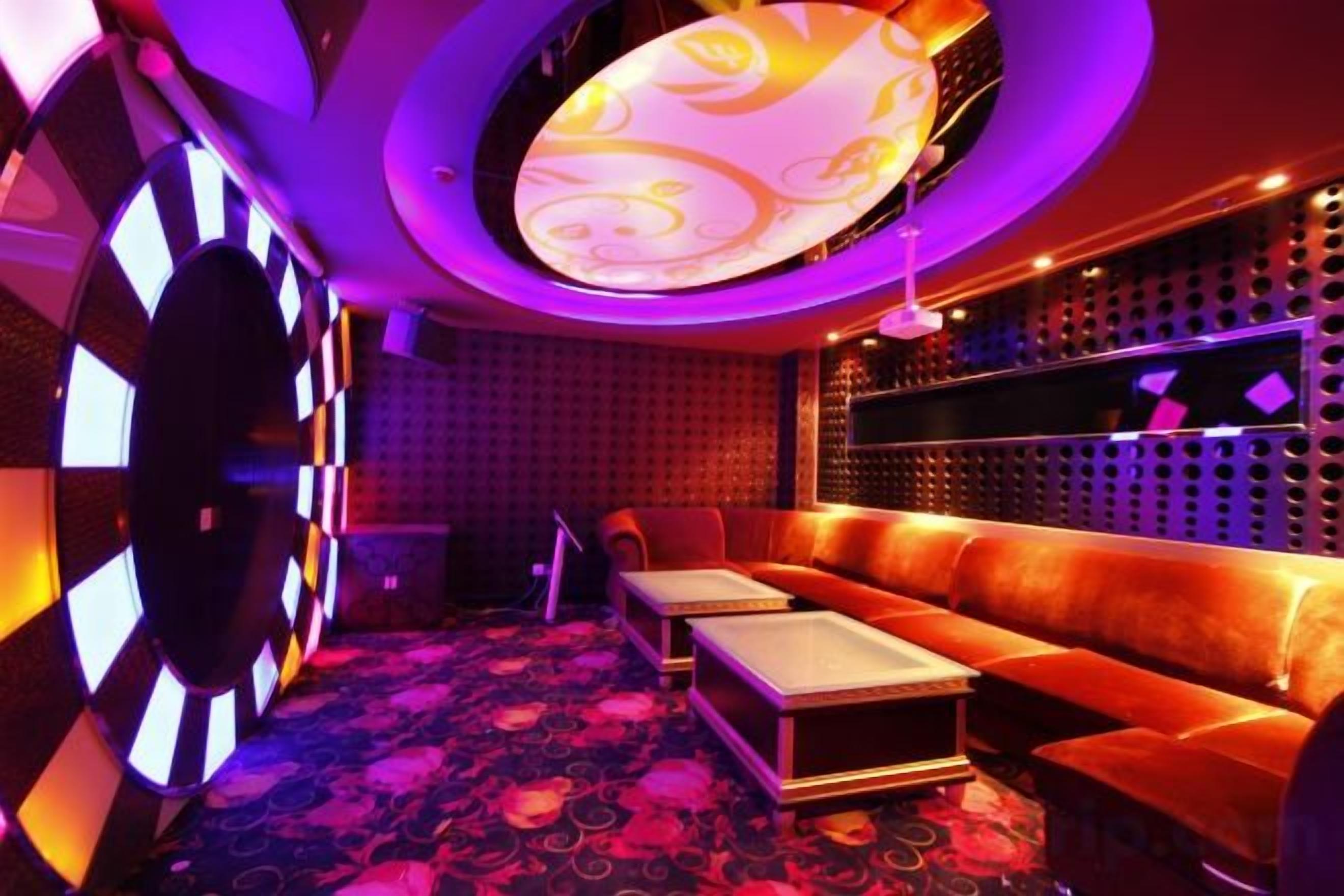 A room with a patterned carpet, a sofa, a small table, and a wall with a patterned design.