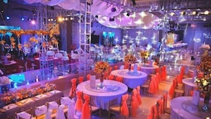 Un salón de banquetes con mesas redondas, sillas y centros de mesa florales.