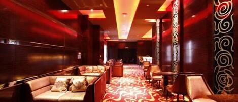 A hotel lobby with a red carpet, seating area, and decorative wall panels.