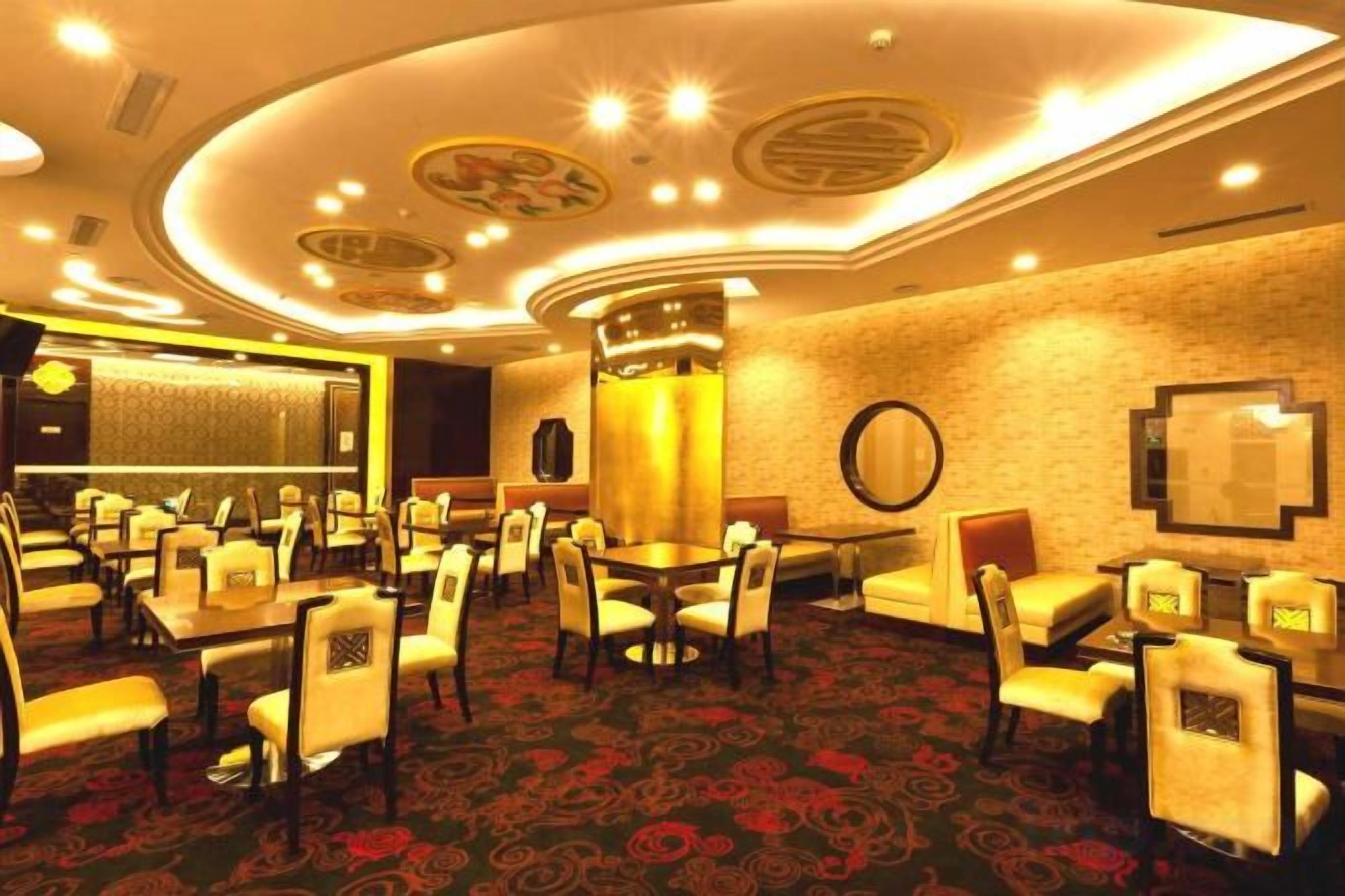 A hotel lobby with multiple seating areas, including round tables and chairs, and a carpeted floor.
