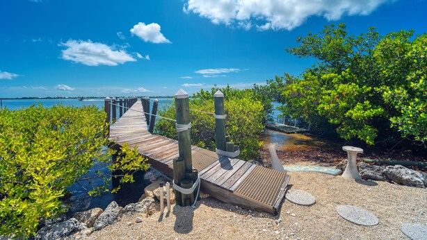 A wooden boardwalk leading to a dock with a clear view of the water and sky.