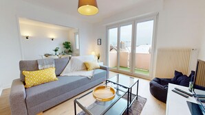 A modern living room with a grey sofa, yellow patterned cushions, a glass coffee table, and a black bean bag. - La belle étape + 1 parking (Colmar)