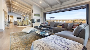 Amplia sala de estar con un ventanal, chimenea y vistas al paisaje desértico.