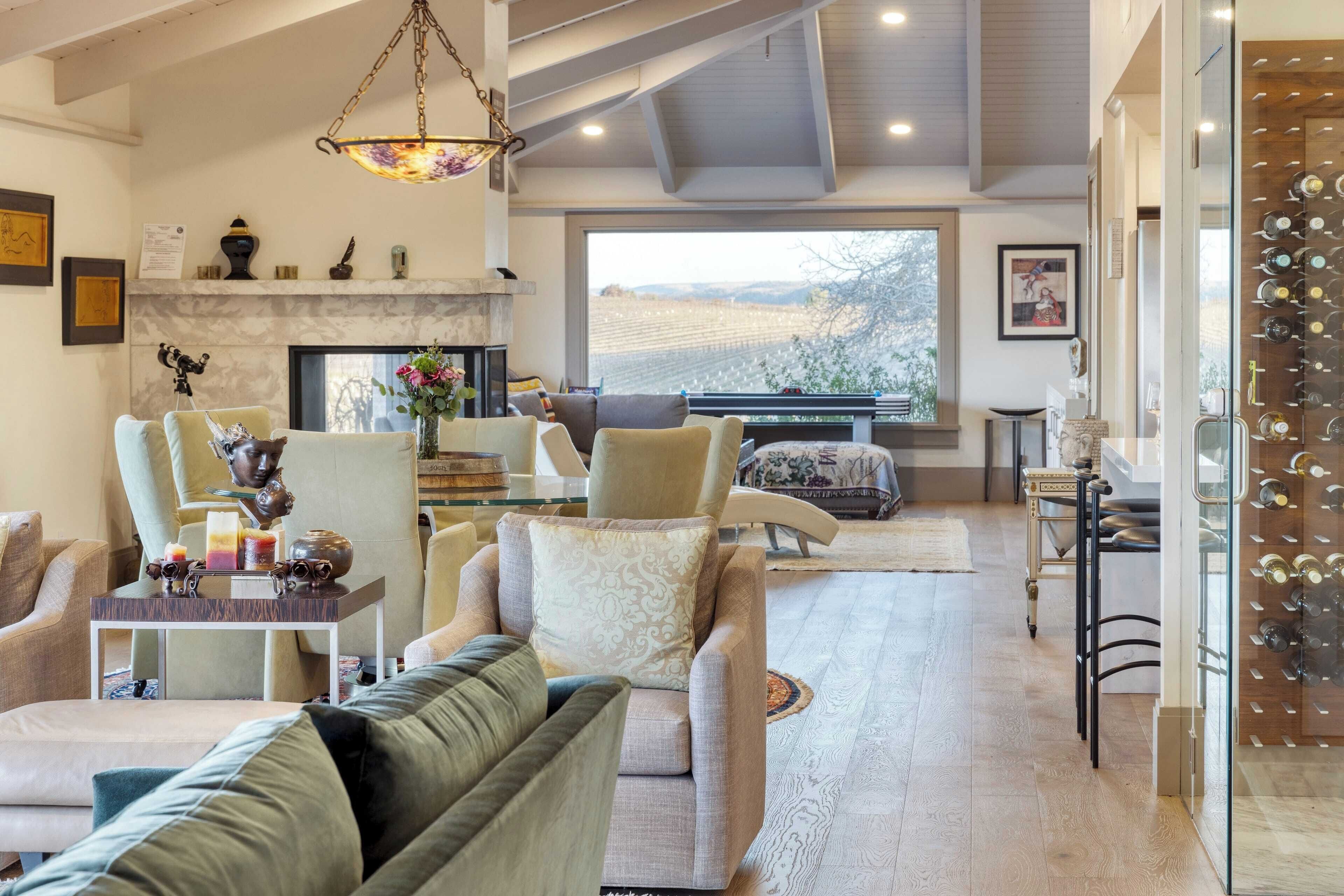 A spacious living room with a fireplace, comfortable seating, and a wine rack.
