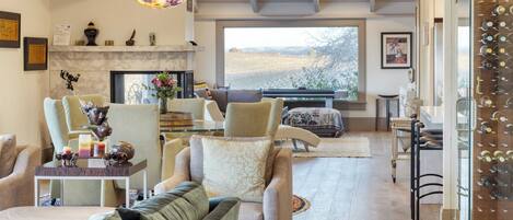 A spacious living room with a fireplace, comfortable seating, and a wine rack.