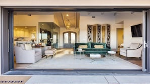 A modern living room with a green sofa, a coffee table, and a dining area visible through the glass door. - Private Pool, Firepit & Wine Room Near Top Paso Wineries Devi Ranch (Paso Robles)