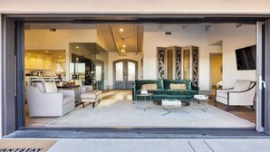 Amplia sala de estar con un sofá verde, sillones blancos y una mesa de centro.