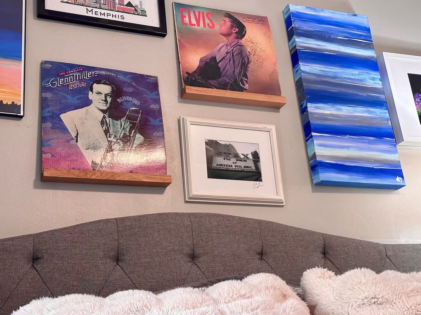 A wall with framed posters and a painting.