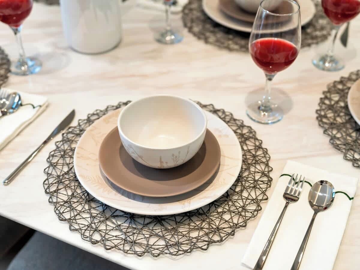Una mesa dispuesta con un bol, platos y cubiertos, rodeada por una malla decorativa.