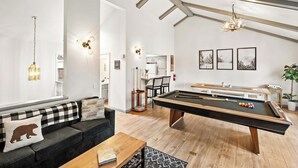 Una sala de estar moderna con mesa de billar, un sofá con cojín a cuadros y una mesa de centro.