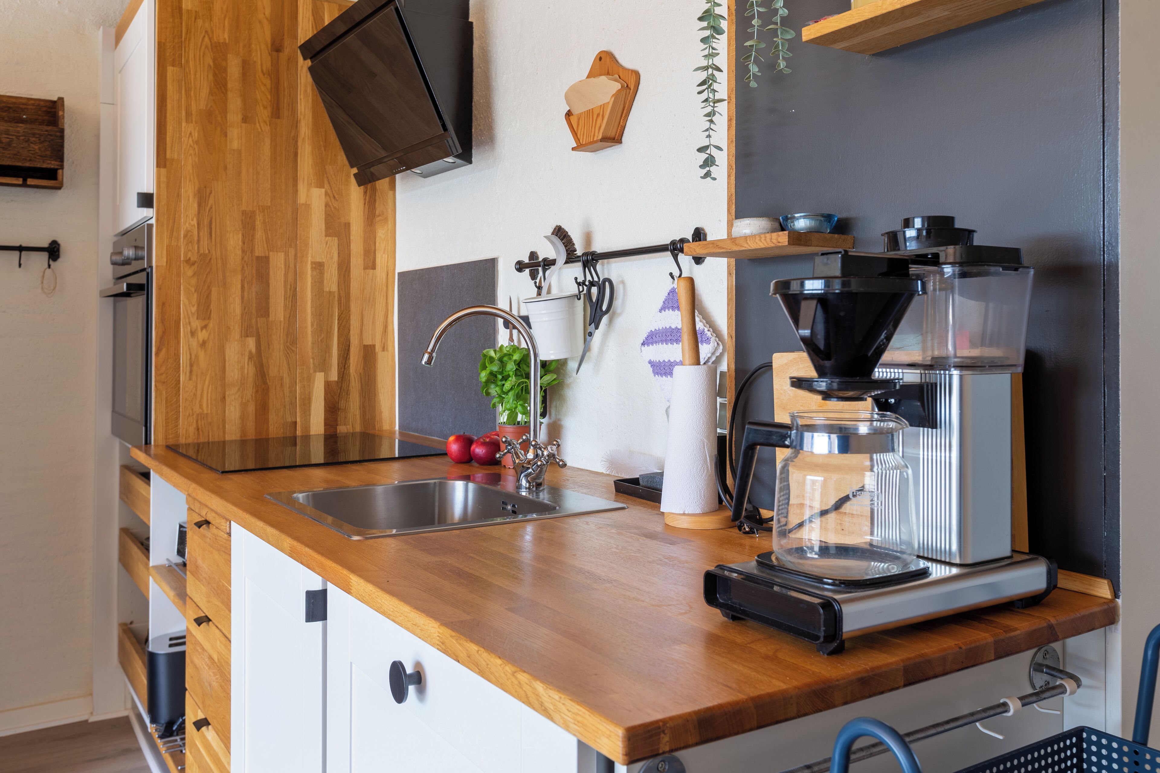 Eine Küche mit Holzarbeitsplatten, einer Kaffeemaschine, einem Spülbecken und einem Blumentopf.