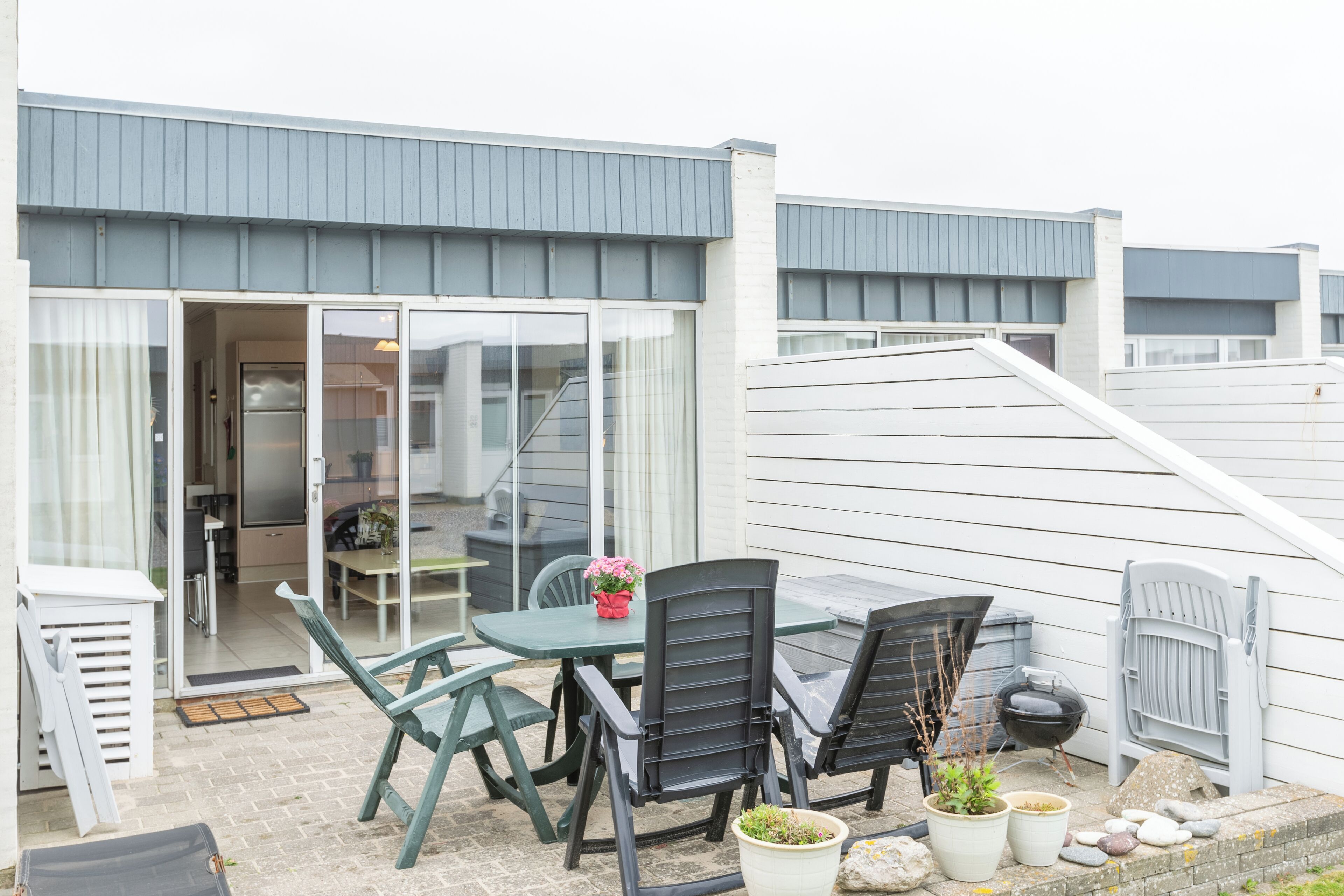 A patio with a table and chairs, a potted plant, and a barbecue grill.