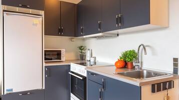 A modern kitchen with dark cabinets, a built-in oven, a microwave, and a stainless steel sink.