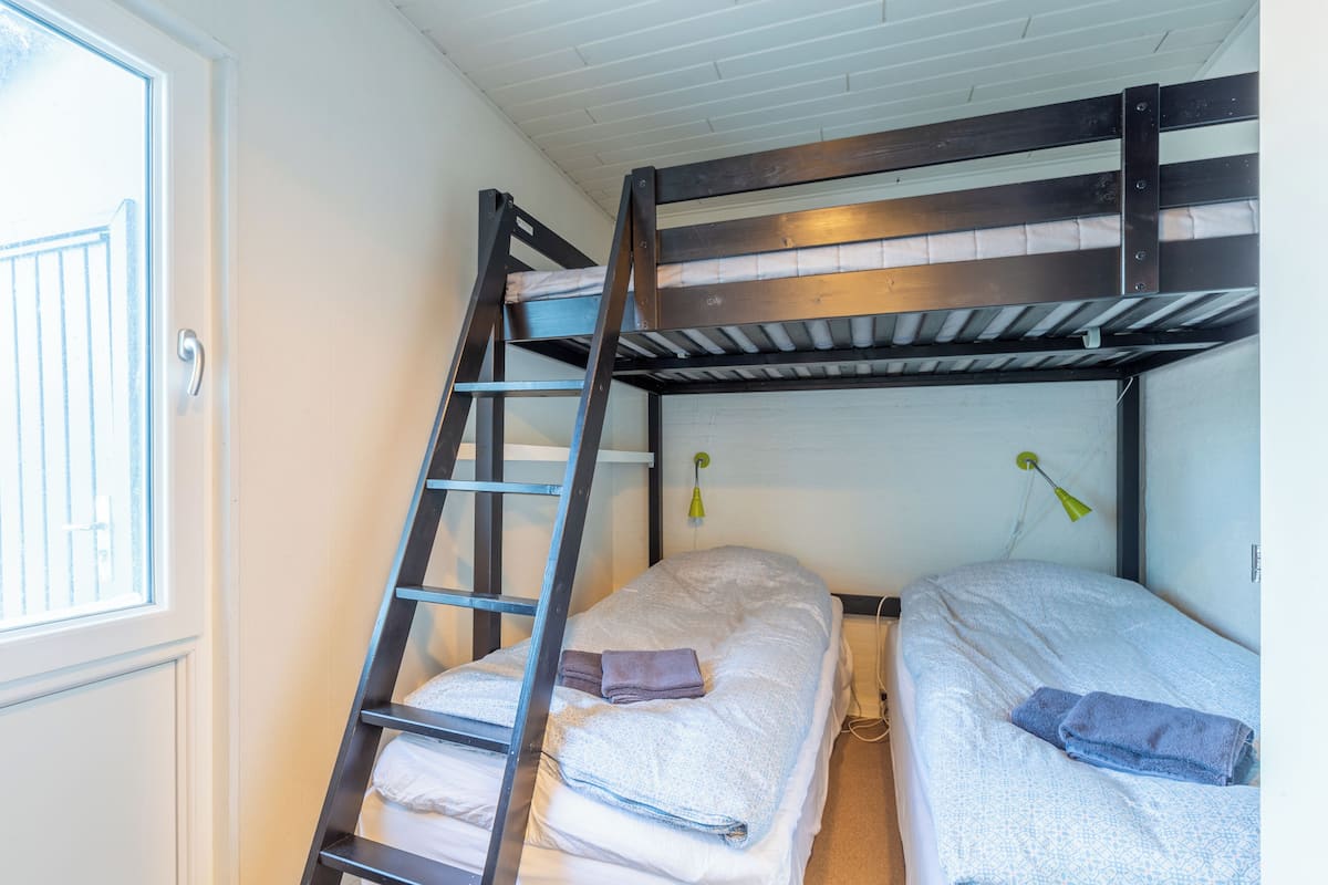 Ein Stockbett mit einer Leiter, einem kleinen Schreibtisch und einem Fenster.
