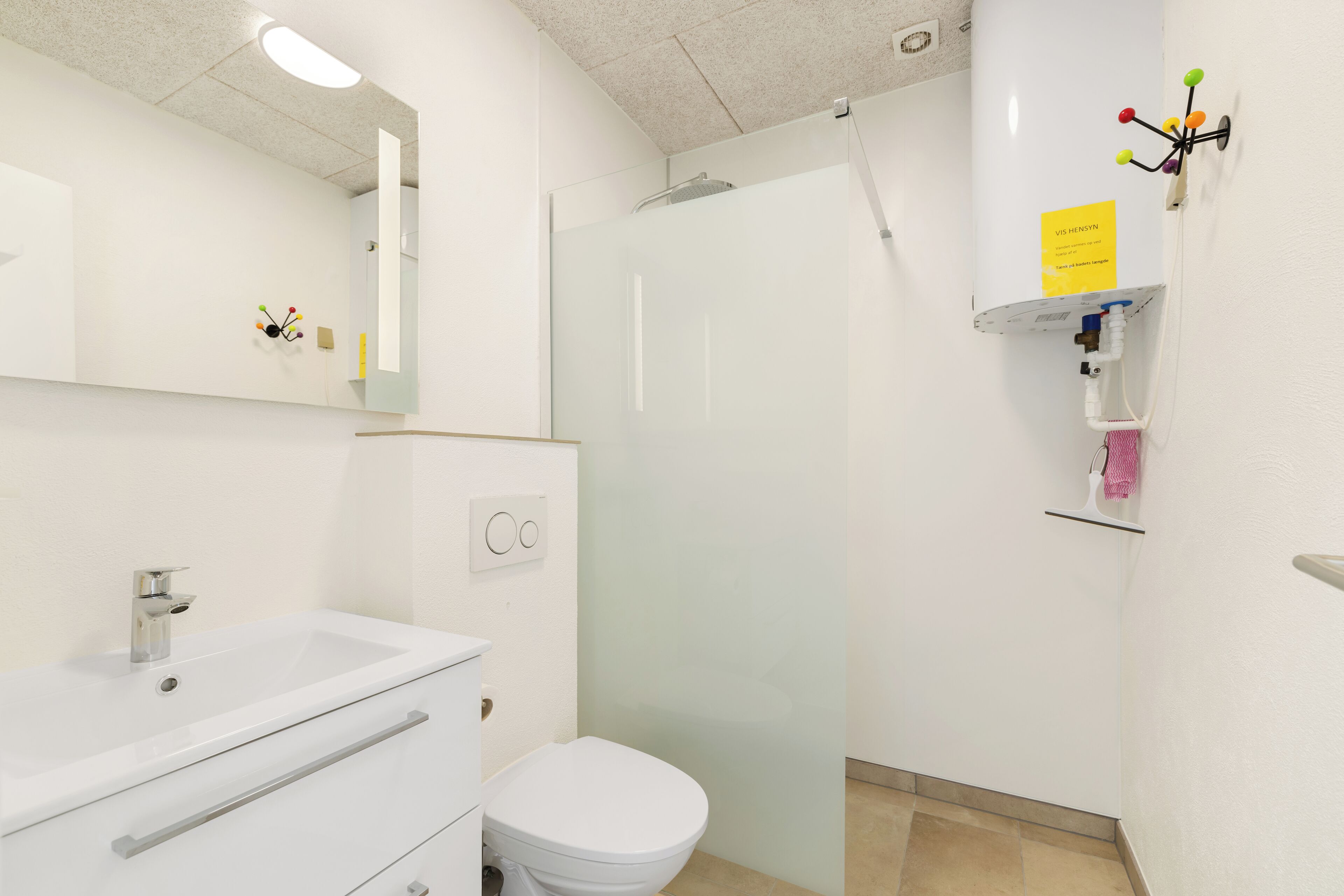 A modern bathroom with a white sink, toilet, and glass shower enclosure.