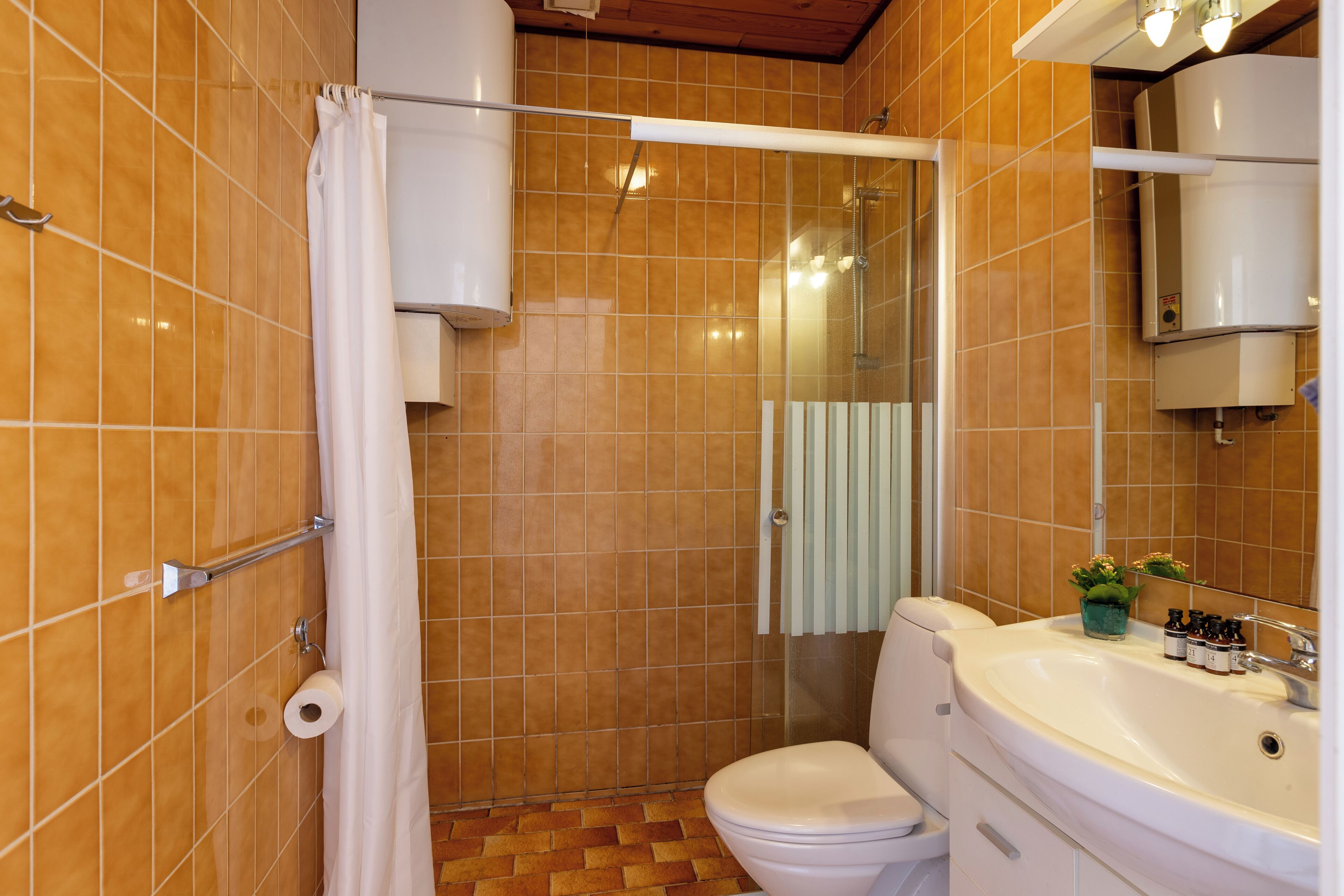 A bathroom with a shower, toilet, sink, and a mirror.
