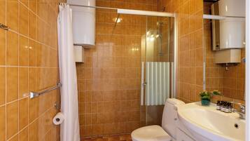 A bathroom with a shower, toilet, sink, and a mirror.