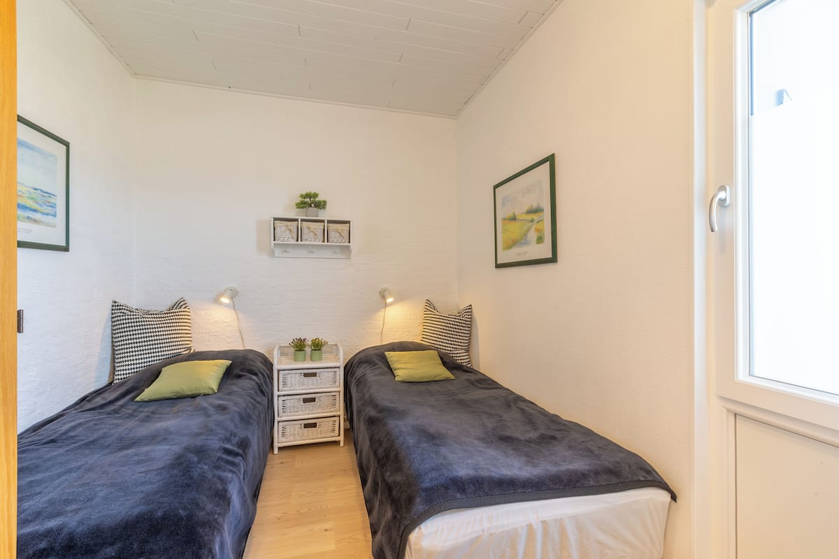 Ein Schlafzimmer mit zwei Betten, einem Regal mit Pflanzen und gerahmten Bildern an den Wänden.